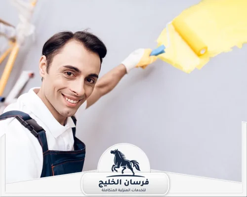 صباغ رخيص في الفجيرة - فرسان الخليج صباغ يرتدي ملابس العمل ويطلي الجزء العلوي من الجدار باللون الأصفر.