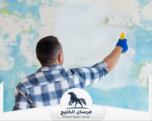 معلم دهان في الفجيرة - فرسان الخليج صباغ يطلي جدارًا متقشرًا باللون الأبيض باستخدام رول دهان.