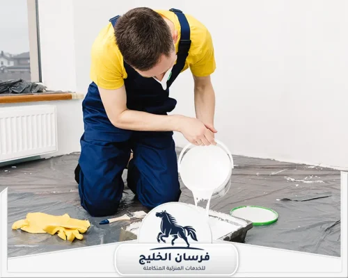 صباغ شاطر في الشارقة - فرسان الخليج صباغ يجهز الدهان الأبيض قبل بدء طلاء الجدران، بينما تغطي الأغطية البلاستيكية أرضية الغرفة.