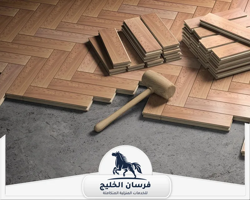 تركيب باركيه خشب عجمان - فرسان الخليج قطع باركيه خشبية مرتبة مع مطرقة تركيب توضح دقة العمل وتجهيز الأرضيات.