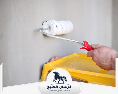 فني صباغ في عجمان - فرسان الخليج عامل صباغة يوزع الدهان على الحائط باستخدام رول صغير.