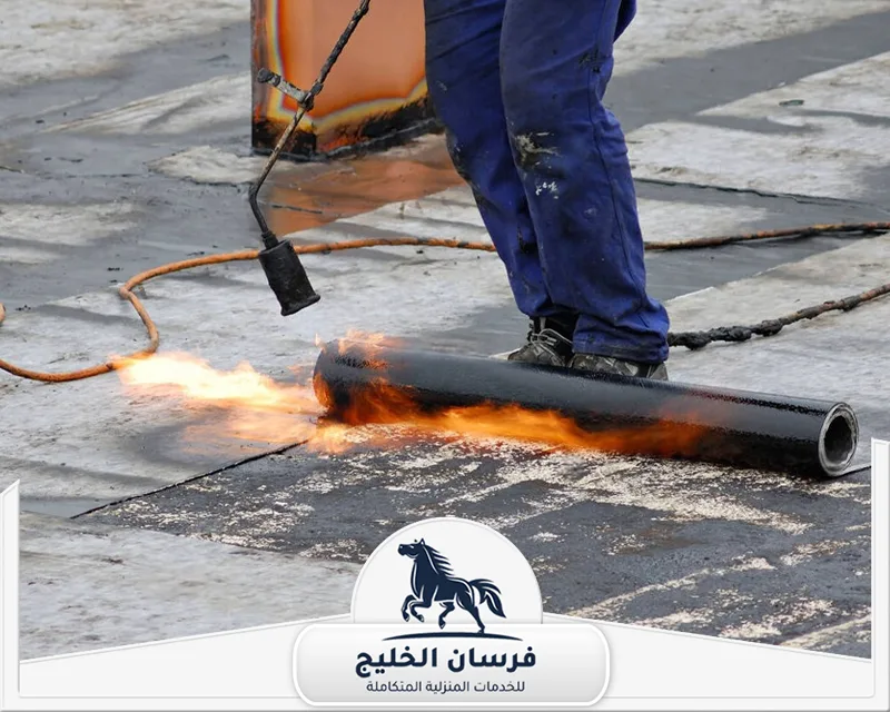افضل شركة عزل اسطح في ابوظبي - فرسان الخليج فني يطبق لفائف العزل المائي فوق السطح باستخدام موقد حراري.