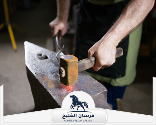 حداد يطرق قطعة حديد ساخنة فوق السندان لتشكيلها بدقة داخل الورشة.