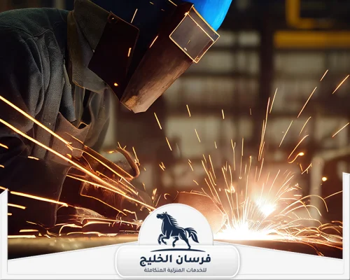 رقم حداد في عجمان 0547761153 فرسان الخليج عامل حدادة يثبت قطعًا معدنية باستخدام جهاز اللحام الكهربائي.