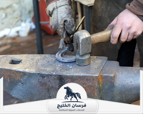 رقم حداد في دبي 0547761153 فرسان الخليج حداد يطرق قطعة حديد منحنية لتجهيزها بالشكل المطلوب.