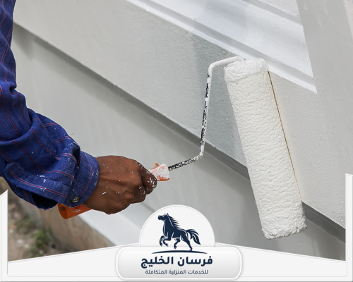 صباغ ديكور في عجمان 0547761153 فرسان الخليج عامل دهانات يطلي واجهة خارجية باللون الأبيض باستخدام رول الطلاء.