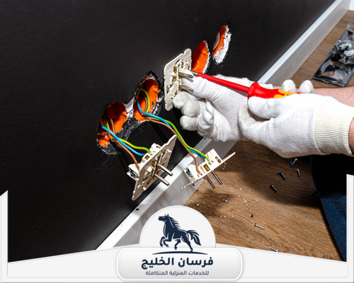 مميزات كهربائي منازل في الشارقة 0547761153 فرسان الخليج كهربائي يصلح عدة مقابس كهرباء داخل جدار أسود باستخدام مفك معزول.