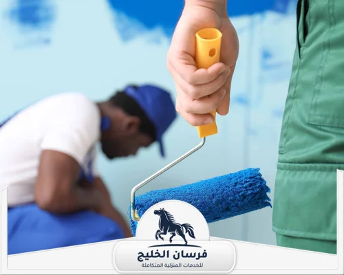 شركة دهانات في عجمان - فرسان الخليج عامل دهانات يمسك رول طلاء أزرق أثناء تنفيذ تشطيبات الجدران.