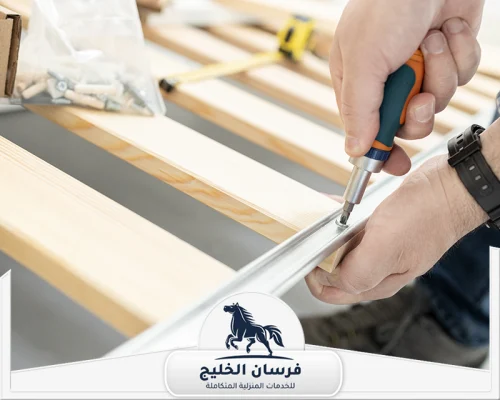 نجار فك وتركيب الاثاث في الفجيرة 0547761153 فرسان الخليج نجار يجمع قاعدة سرير خشبية ويثبتها بالمسامير داخل المنزل.