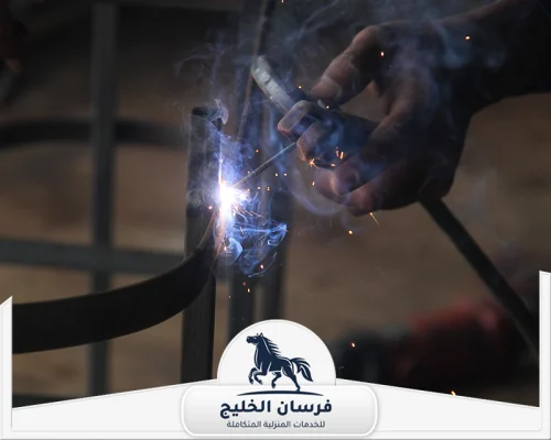 حداد هناجر في عجمان 0547761153 فرسان الخليج فني لحام يثبت هيكلًا معدنيًا باستخدام القطب الكهربائي.