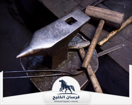 حداد هناجر في الشارقة 0547761153 فرسان الخليج أدوات الحدادة الأساسية موضوعة فوق السندان داخل ورشة العمل.