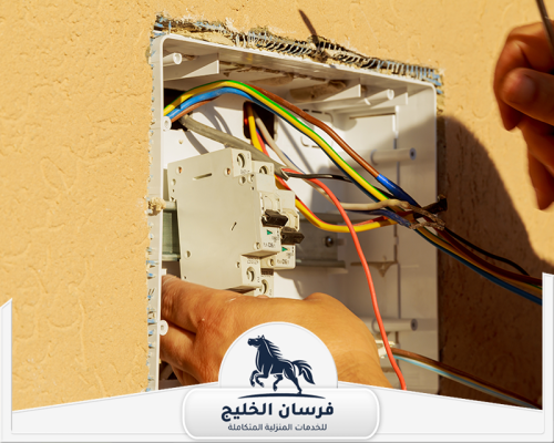 صيانة كهرباء المنزل بالشارقة 0547761153 فرسان الخليج كهربائي يراجع توصيلات الأسلاك داخل لوحة كهرباء منزلية مفتوحة.