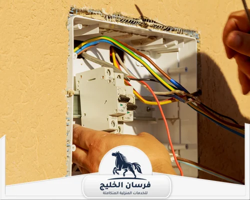 صيانة كهرباء المنزل بالشارقة 0547761153 فرسان الخليج كهربائي يراجع توصيلات الأسلاك داخل لوحة كهرباء منزلية مفتوحة.