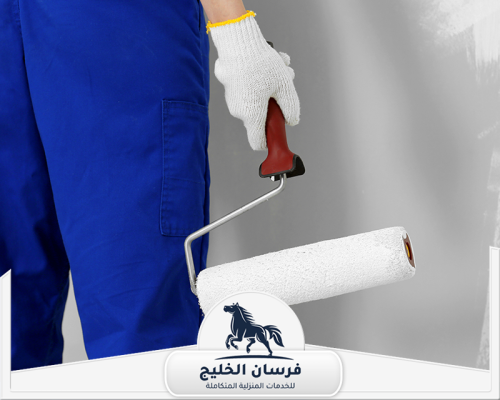 شركة صباغة في رأس الخيمة 0547761153 فرسان الخليج عامل يرتدي ملابس العمل ويمسك رول طلاء لتشطيب الحائط.