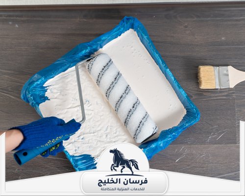 معلم دهان في رأس الخيمة 0547761153 فرسان الخليج رول وفرشاة دهان بجوار صينية مملوءة بالطلاء الأبيض.
