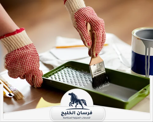 شركة صبغ في عجمان 0547761153 فرسان الخليج عامل يجهز فرشاة الدهان داخل صينية الطلاء قبل بدء العمل.