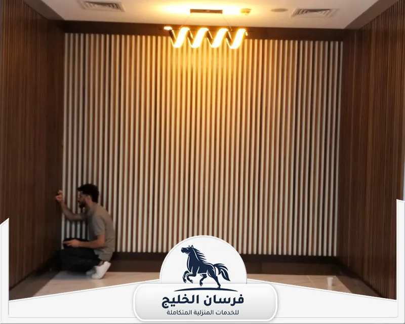 عمال تركيب باركيه في عجمان - فرسان الخليج فني أثناء تركيب ألواح خشبية طولية لإكمال تصميم الجدار الداخلي.