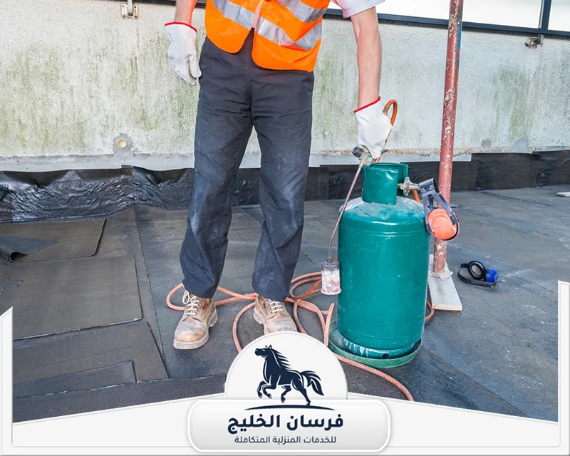 عامل عزل اسطح في دبي - فرسان الخليج فني يجهز سطح المبنى لتطبيق لفائف العزل المائي باستخدام المعدات الحرارية.