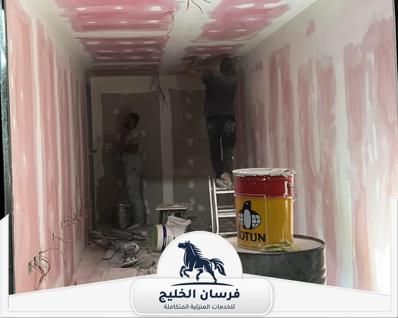 صباغ شاطر في ام القيوين - فرسان الخليج عمال دهانات يعالجون الجدران والأسقف بالمعجون داخل ممر قيد التشطيب.