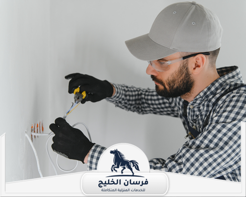فني كهرباء يفحص أسلاك داخل الجدار باستخدام كماشة وأدوات عزل.