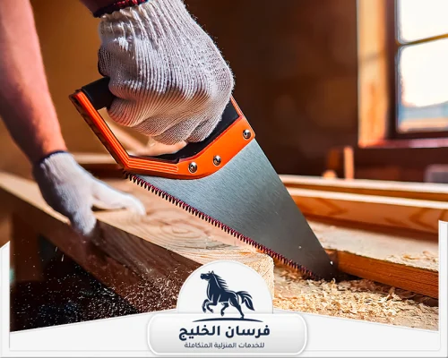 افضل نجار في الشارقة - فرسان الخليج نجار يقطع الخشب بدقة باستخدام منشار يدوي داخل ورشة تجهيز الأثاث.